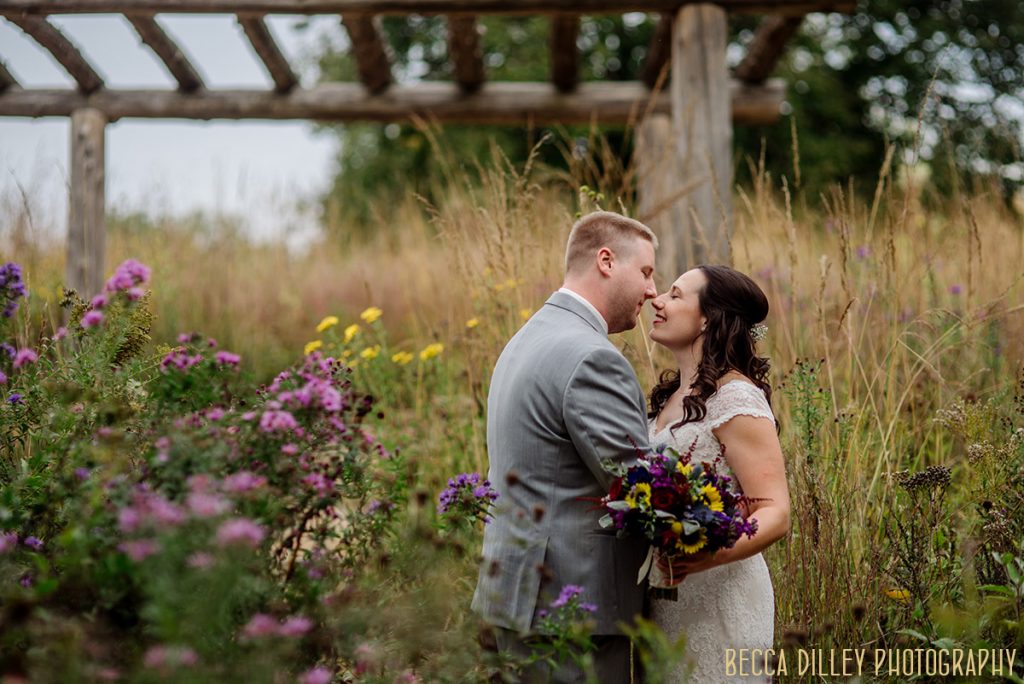 couple embrace in prairie grass before mn arboretum wedding