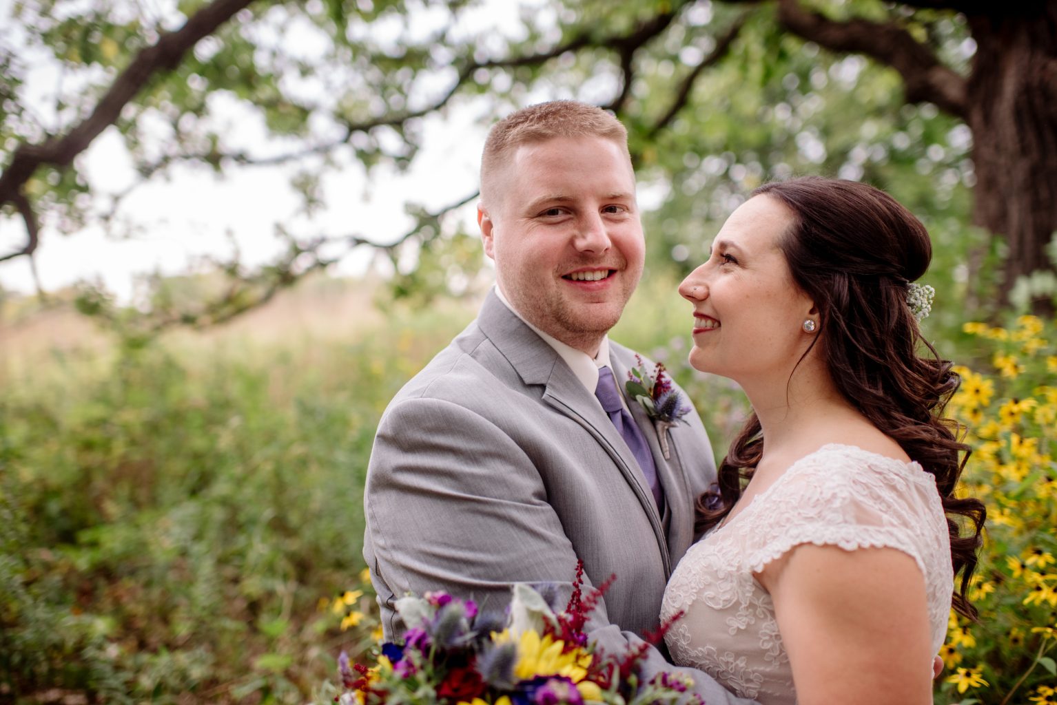 Couple standing in oak savannah with groom looking at camera for mn arboretum wedding