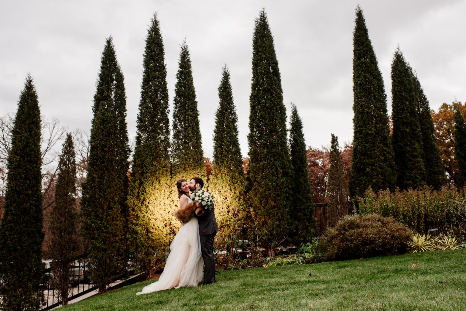 couple in front of tall pines with yellow light behind them for mn arboretum wedding