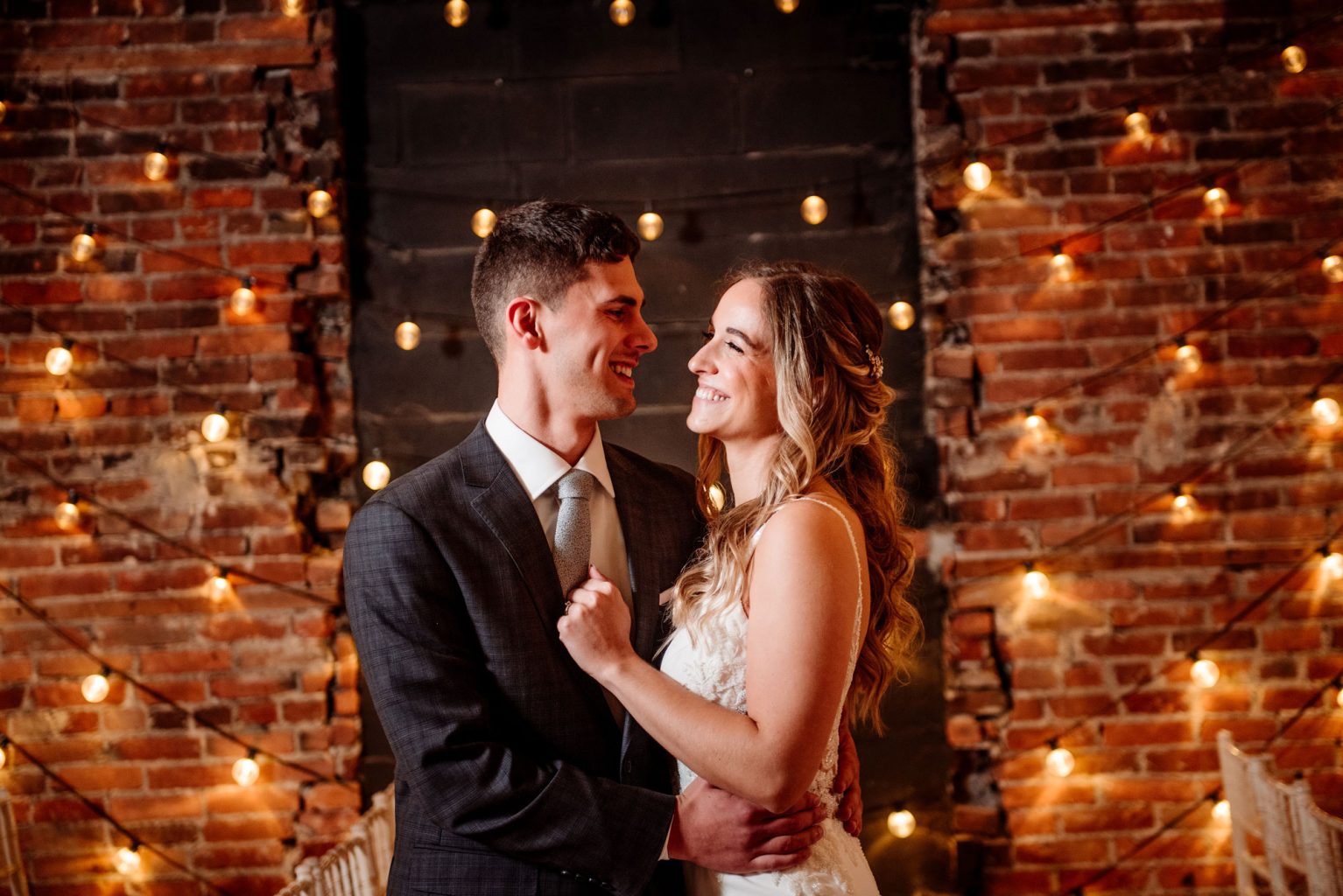 bride and groom smile at each other in the loft at studio j in stillwater mn before their wedding ceremony