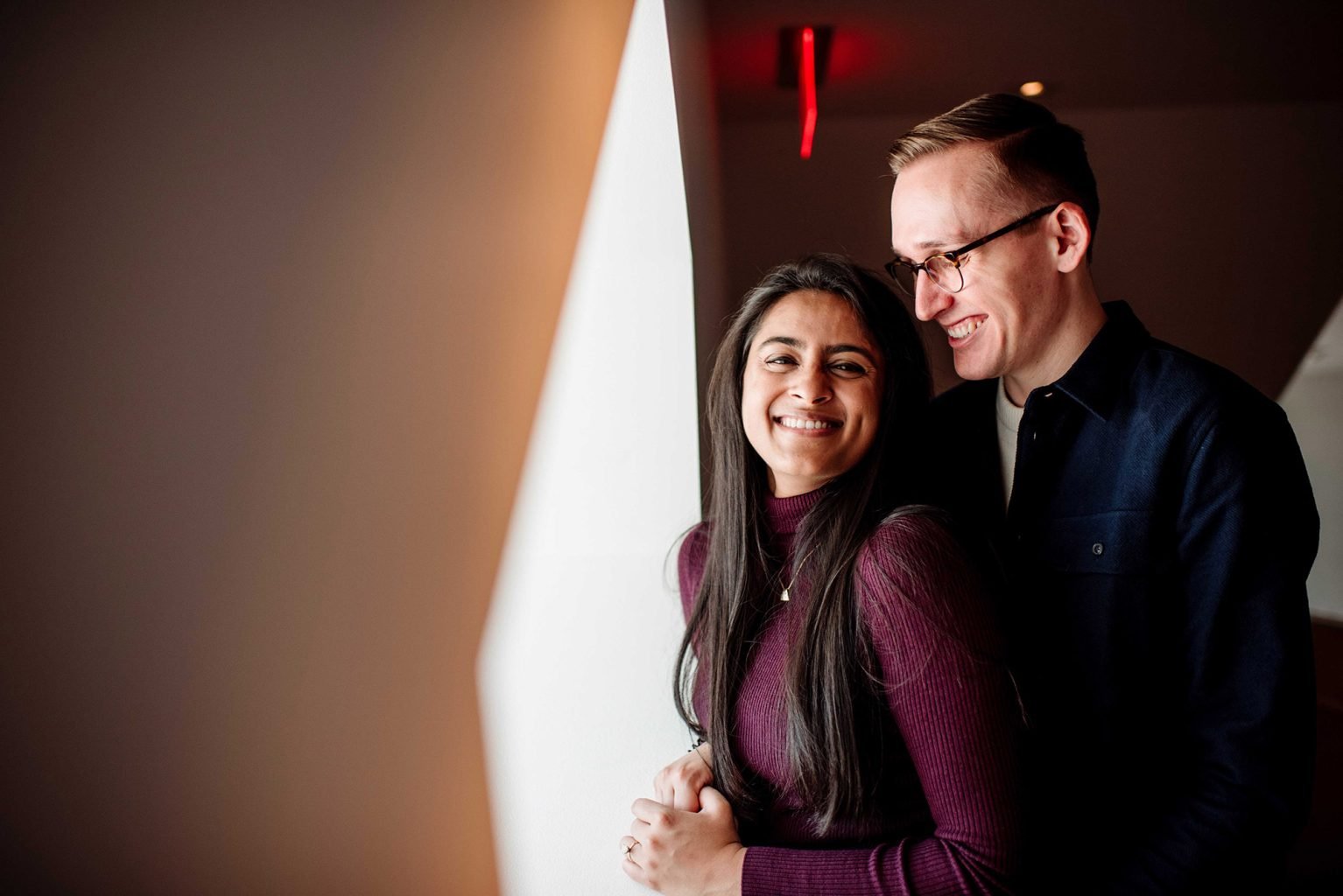couple pose in front of window for engagement photos