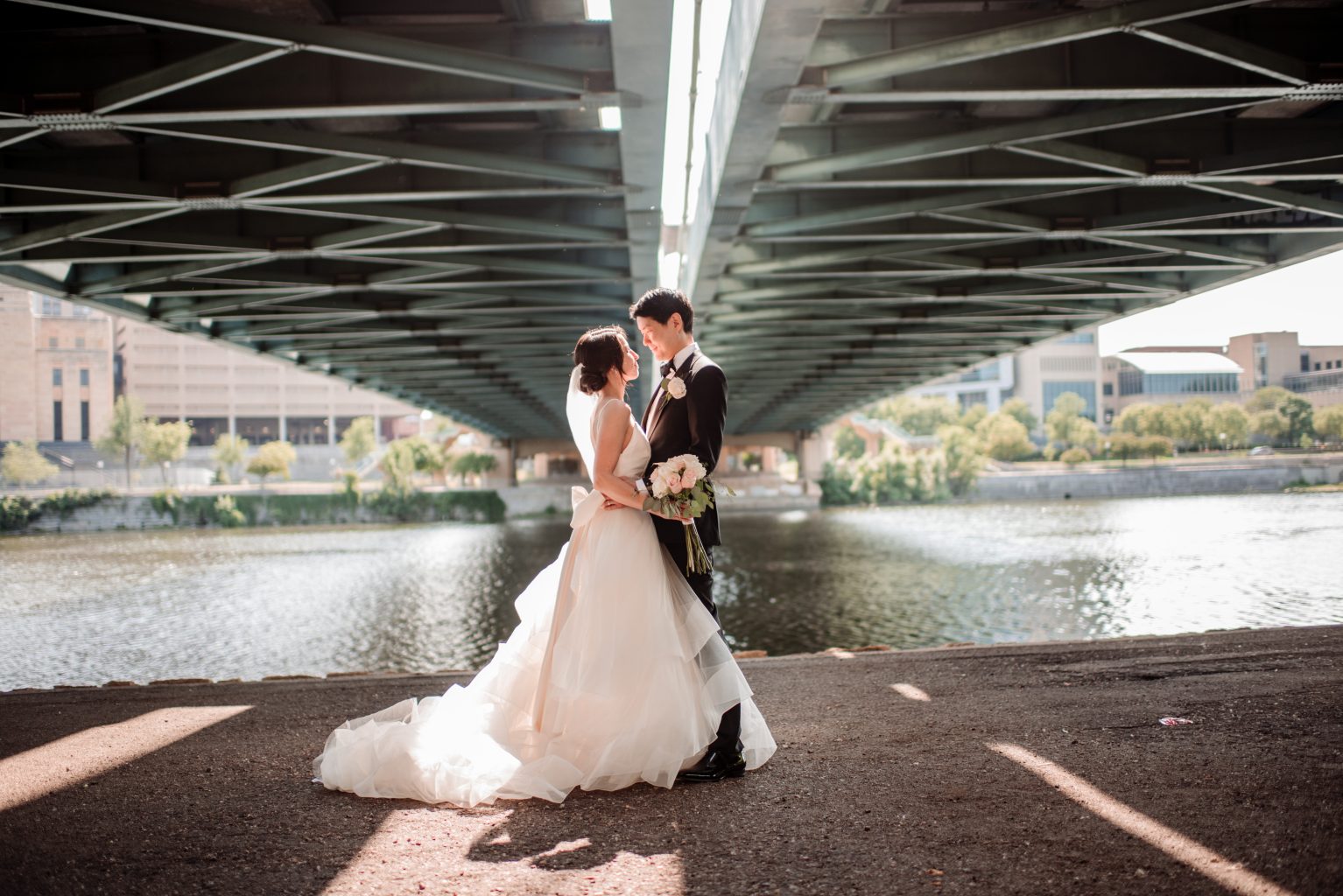 couple under hennepin ave bridge on nicollet island after wedding in minneapolis light coming through the bridge - Portrait Location Guide Twin Cities
